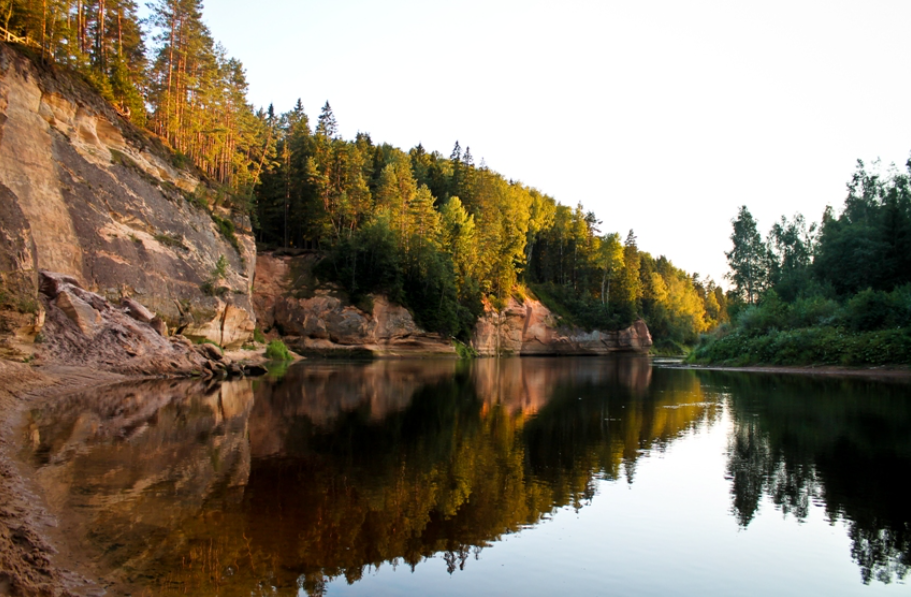The Gauja River at sunset, with sandstone cliffs and pine forest along the water