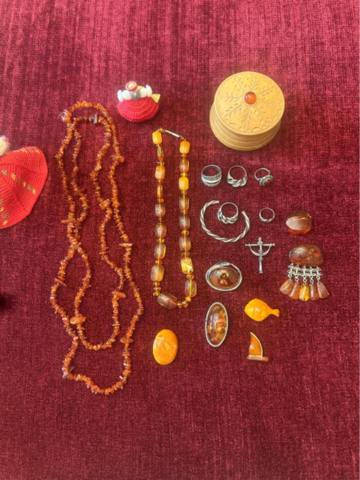 A collection of amber necklaces, rings, and brooches laid out on cloth