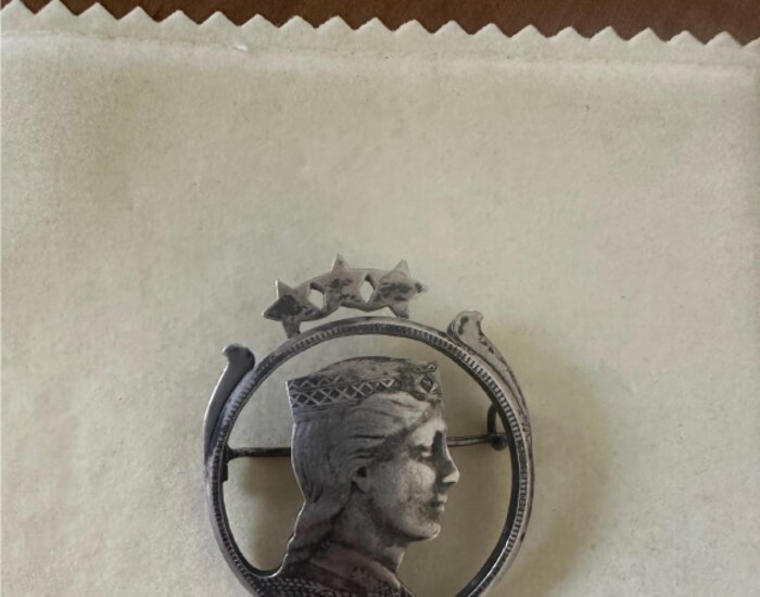 A silver brooch with the profile of a crowned woman